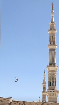 a tall white building with a clock on it's side and a plane flying in the air