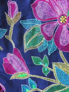 an embroidered fabric with flowers and leaves on it