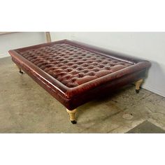 a brown leather ottoman sitting on top of a cement floor