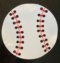 a paper plate that has a baseball on it with red string attached to the top