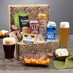 a beer and snacks gift box on a table with two glasses of beer, crackers, cheeses and crackers