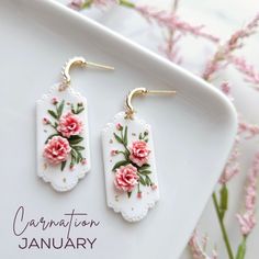 the earrings are decorated with pink flowers and gold earwires on a white plate