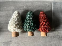 three small crocheted trees sitting on top of a wooden table next to each other