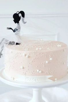 a wedding cake with a bride and groom figurine on top, sitting on a white pedestal