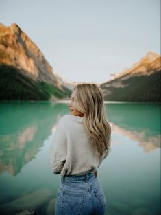 a woman standing in front of a mountain lake