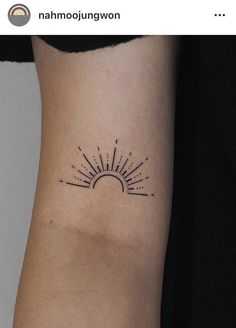 a sun tattoo on the left arm with lines coming out of it's center