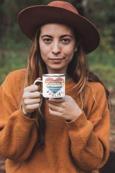 a woman wearing a hat holding a coffee mug