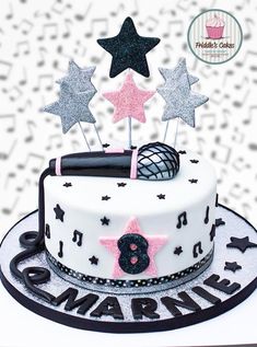 a birthday cake decorated with stars, music notes and a microphone on top is shown