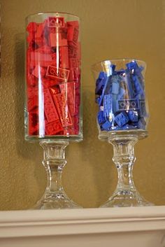 two glasses filled with legos sitting on top of a mantle