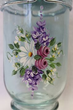 a glass jar with flowers painted on it