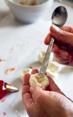 a person holding a spoon over a peeled piece of food on a table with other items in the background