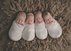 four newborn babies are sleeping on a brown blanket together with their arms around each other