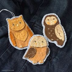 three felt owl ornament hanging from a string on a blue jean jacket,