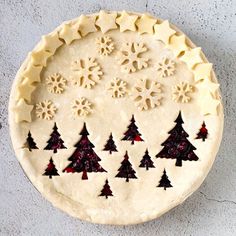 an uncooked pie with snowflakes and trees on it