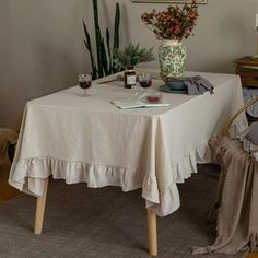 there is a table with a white cloth on it and some plants in the corner