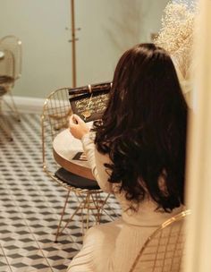 a woman sitting at a table in front of a cake on top of a black and white checkered floor