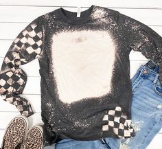 a black and white sweater with checkerboard print on the front, jeans and leopard slippers