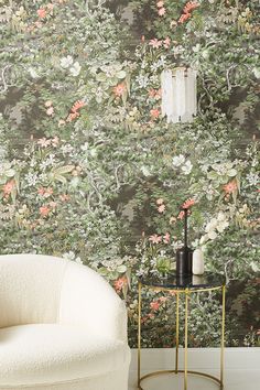 a white chair sitting in front of a wallpapered with pink and green flowers