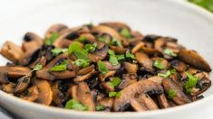 a close up of a bowl of mushrooms with green garnish on the side