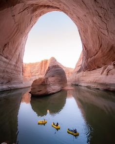 three kayakers are in the middle of a large body of water near a rock formation