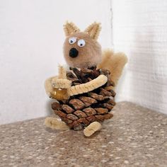 a stuffed squirrel is holding a pine cone