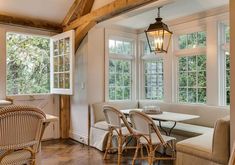 a living room filled with lots of furniture next to two large windows on top of a wooden floor