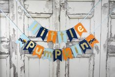 a banner that says little pumpkin hanging from a string in front of an old door