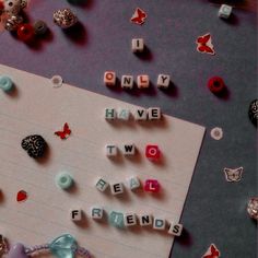 the word friends spelled with letters on a piece of paper surrounded by beads and butterflies