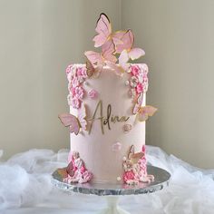 there is a pink cake with butterflies on it and the name apue written on top