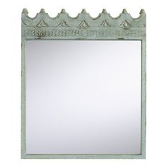 a mirror that is sitting on top of a white wall with an ornate design around it