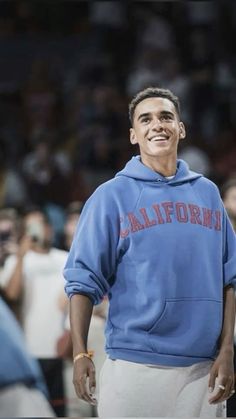 a man standing in front of a crowd wearing a blue hoodie