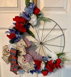 a wreath with red, white and blue flowers hanging on a door