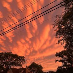 the sky is filled with clouds and some power lines are in the foreground at sunset