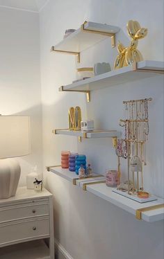 the shelves are filled with jewelry and other decorative items in this white, gold - trimmed room