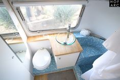 a bathroom with a toilet, sink and window in the room that looks out onto trees