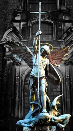 an angel statue on top of a cross in front of a building