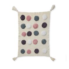 a white pillow with multicolored pom poms on it