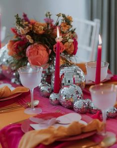 the table is set with pink and orange decorations, silverware, candles, and napkins