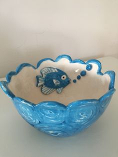 a blue and white bowl sitting on top of a table next to a vase with a fish in it