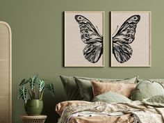 two butterfly prints hanging on the wall above a bed with pillows and blankets, next to a potted plant