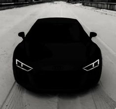 a black sports car driving down a snow covered road