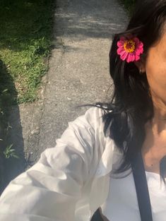 a woman with a flower in her hair taking a selfie on the street side