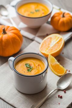 two white bowls filled with soup on top of a table next to sliced oranges