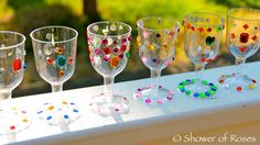 five wine glasses are lined up on a window sill with colorful beads in them