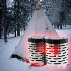 two black and white barrels sitting in the snow next to a teepee tent with red lights on it