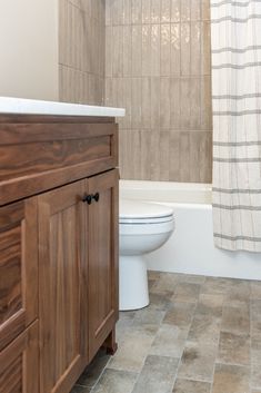 a white toilet sitting next to a bath tub in a bathroom on top of a tiled floor