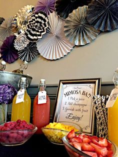 a table topped with fruit and drinks next to paper fan wall art hanging on the wall