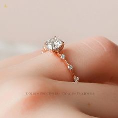 a close up of a person's hand holding a ring with a diamond on it