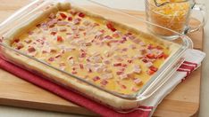 a casserole dish with ham and cheese in it on a wooden cutting board