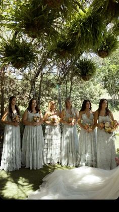 a group of women standing next to each other in front of trees with flowers on them